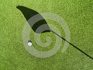 Golf ball on the green, shadow of a flagÃÂ on a green,ÃÂ golf course photo